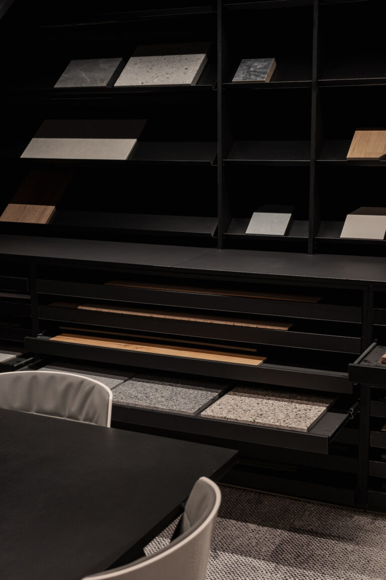 Detail of Eaglestone’s materials library showcasing a curated selection of stone, wood, and textile finishes arranged in black display shelves.