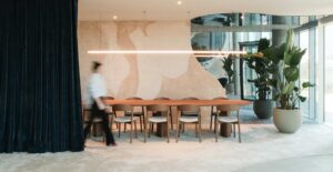 Contemporary dining area with long wooden table, natural-toned wall mural, and indoor plants, designed by ncbham for Xenon Building