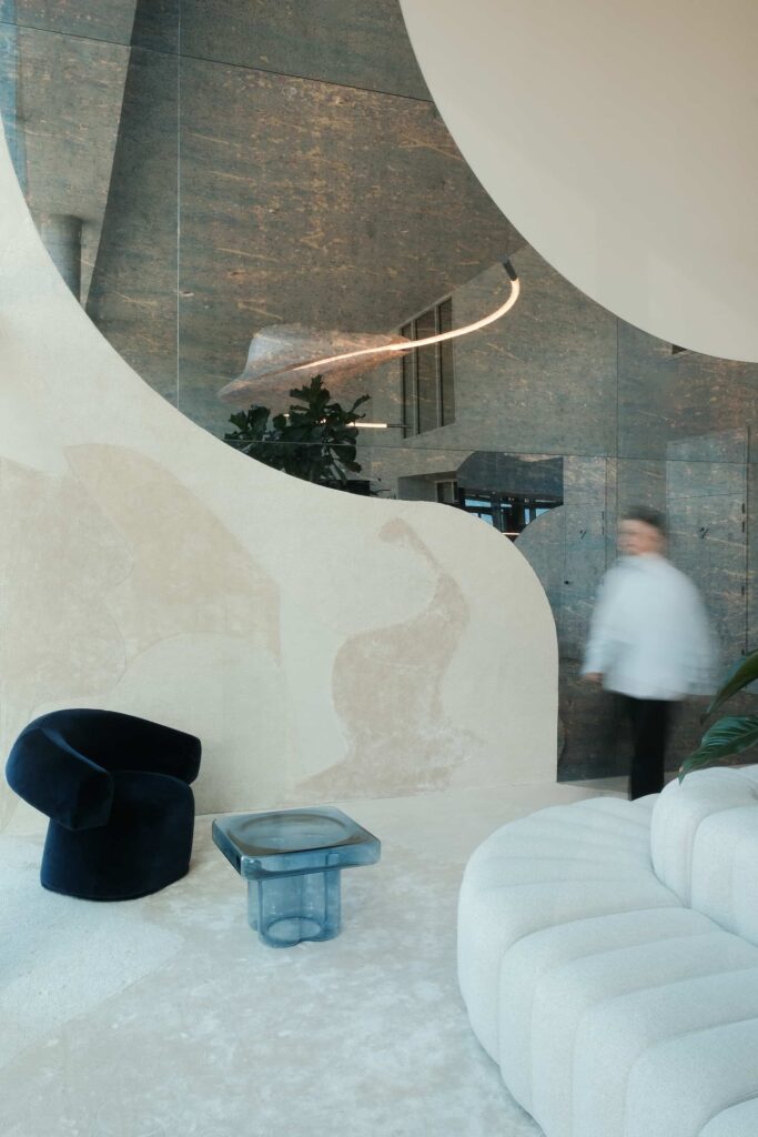 Curved beige textile wall panel meets reflective stone surface with light grey tiled flooring