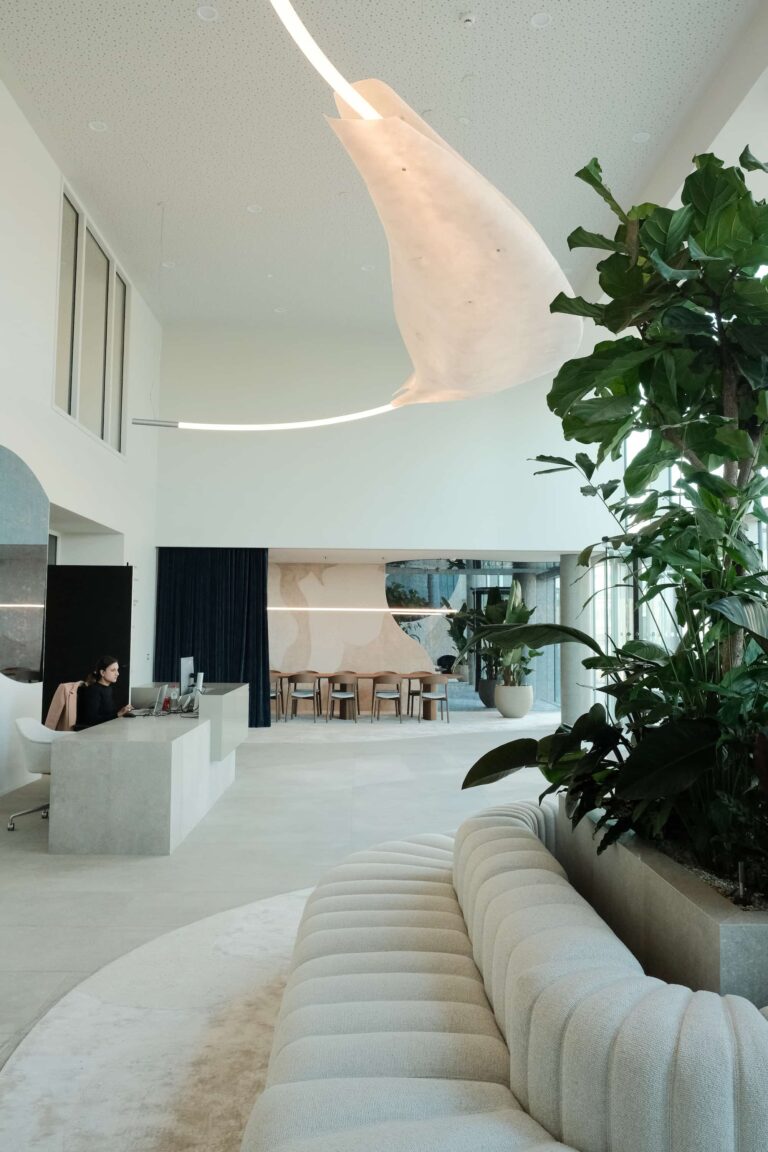 Reception area with custom desk, curved white sofa, and natural light flooding the double-height lobby in Xenon Building