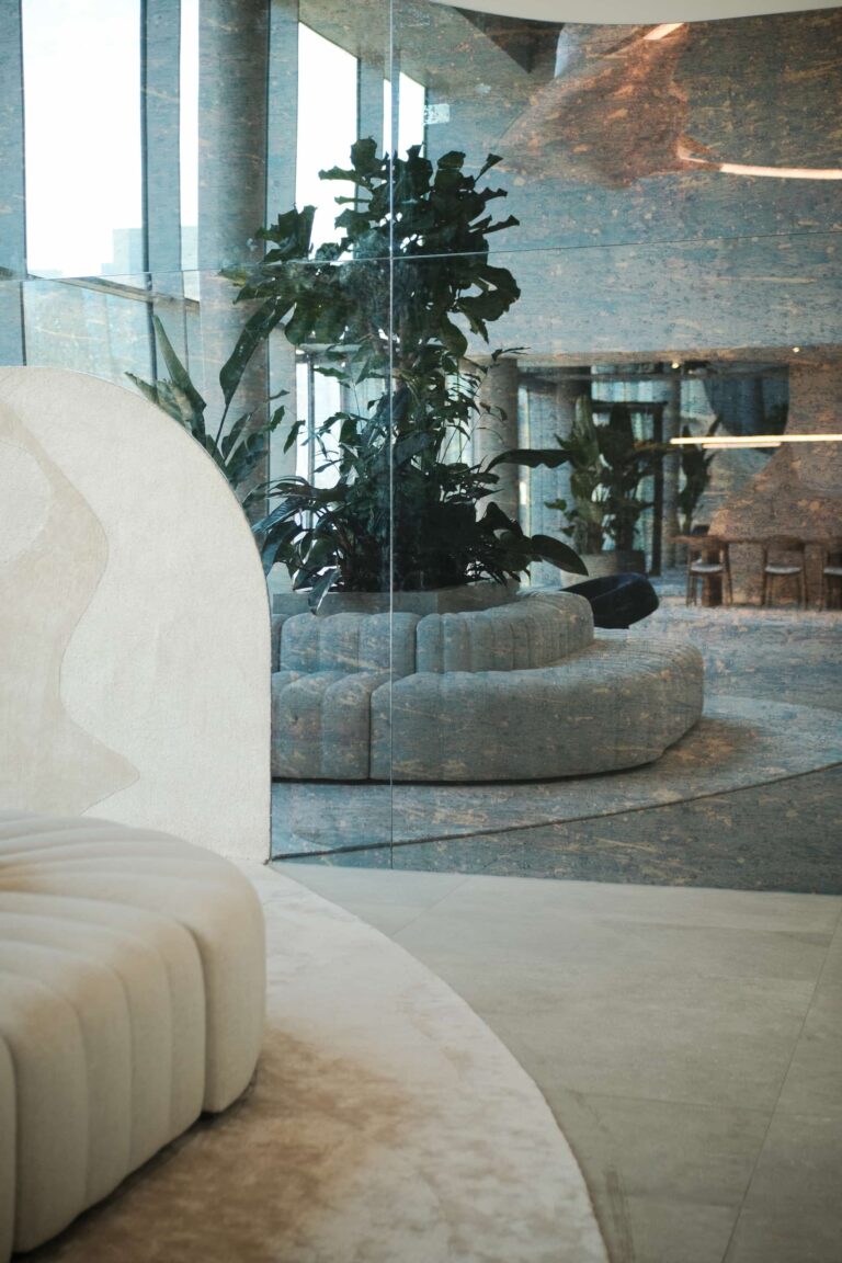 Reflection of biophilic interior with central circular sofa and indoor plants on curved mirrored wall