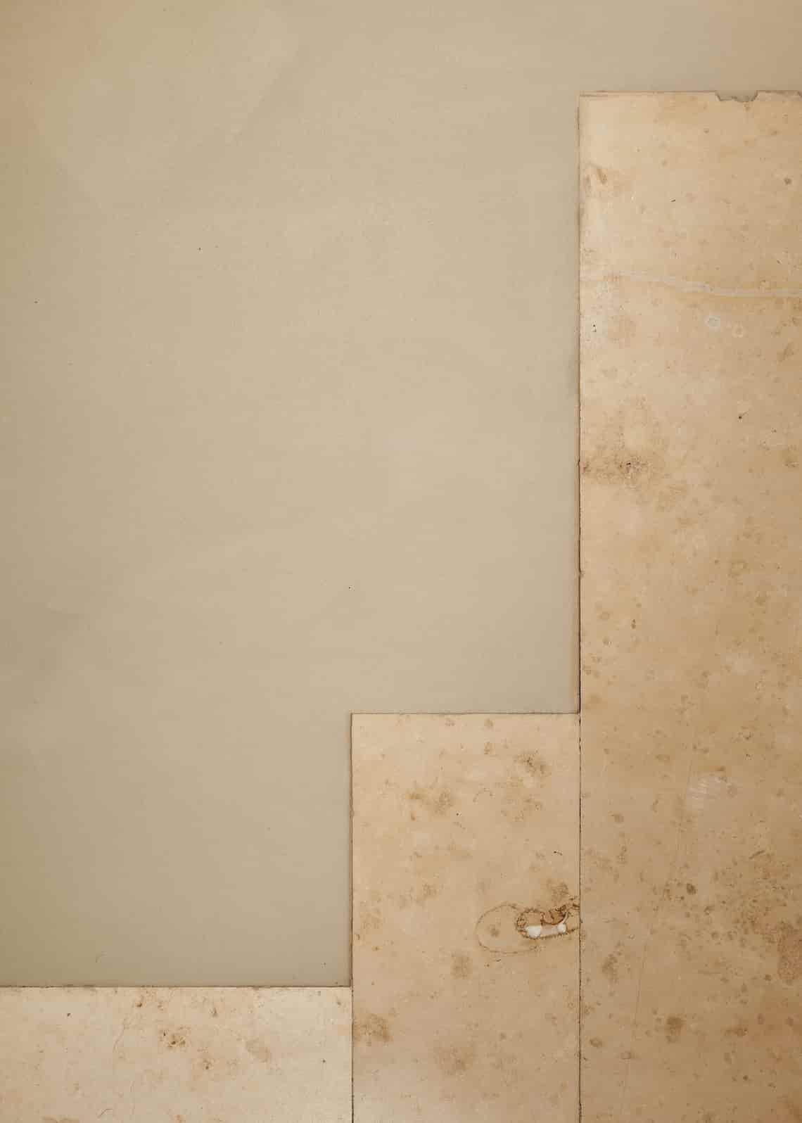 Detail of flooring showing the transition between smooth beige concrete and irregular stone tiles.