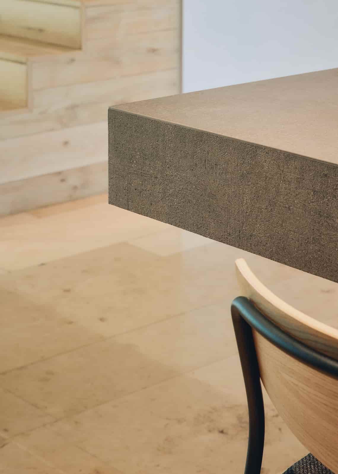 A light wood and metal chair beside a thick, textured tabletop in a bright modern setting.