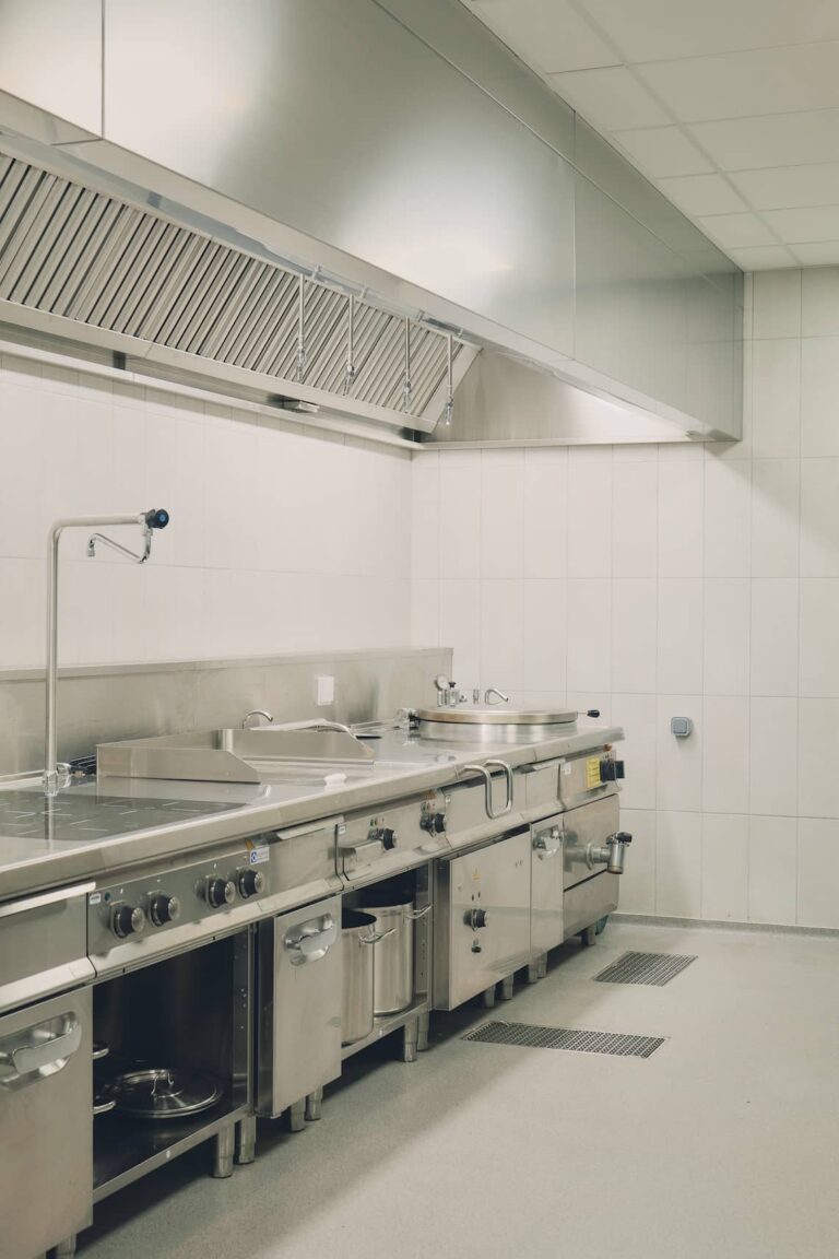 Professional stainless steel kitchen with induction cooktops and industrial extractor hood