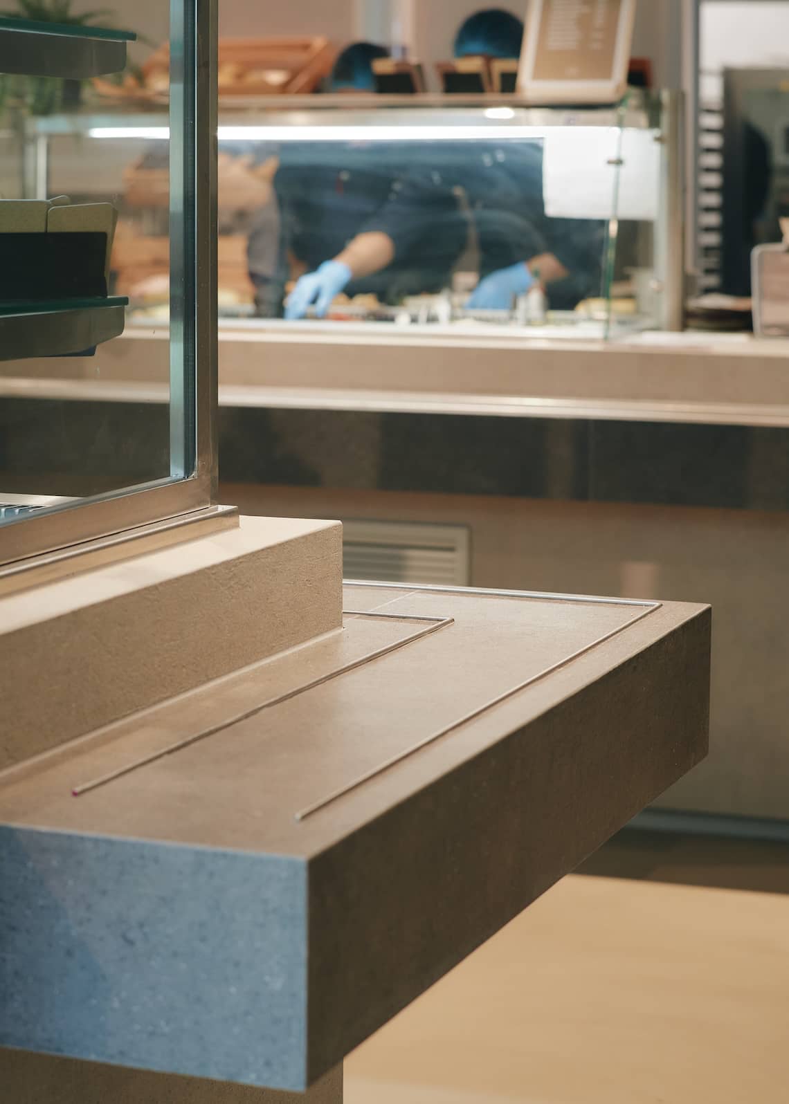 Minimalist food counter with integrated surfaces and display cases in a sustainable kitchen