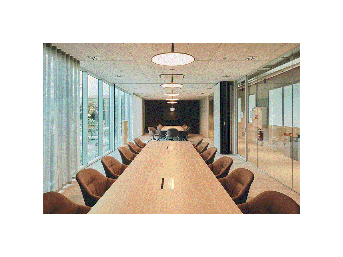 Man walking through a modular meeting room, activating sliding partition walls to separate the meeting room into two areas